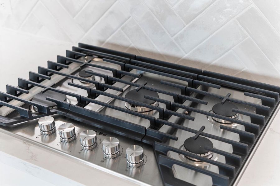 Sleek Whirlpool 30-inch stainless steel gas cooktop features five powerful burners and continuous heavy-duty cast-iron grates.