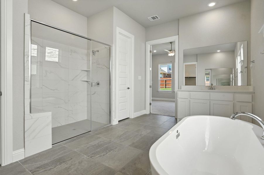 Full bathroom featuring a soaking tub, a marble finish shower, vanity, a ceiling fan, and recessed lighting