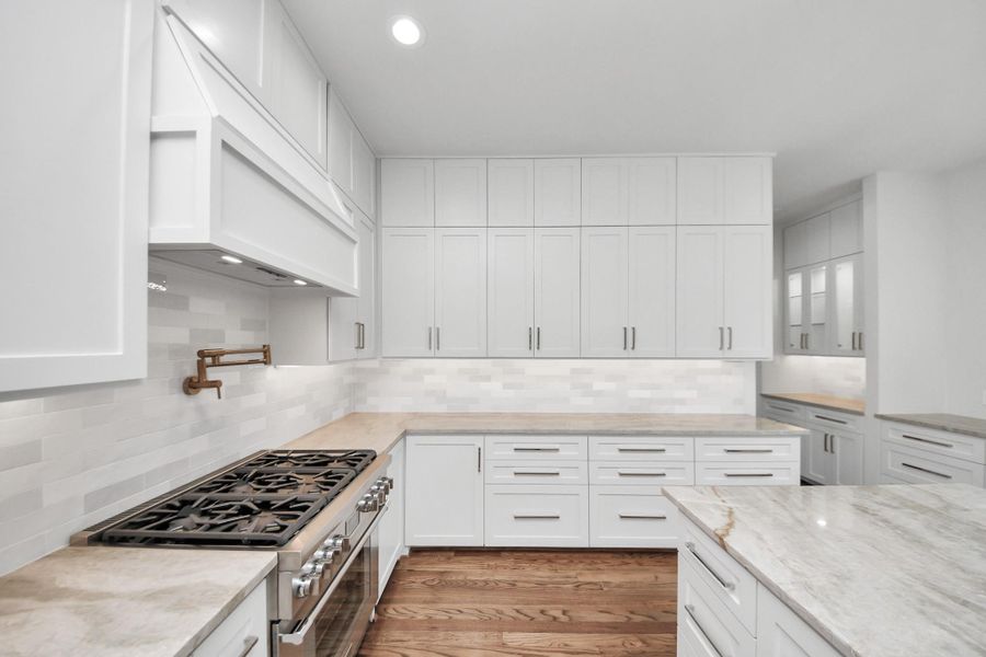 Designed with the serious cook in mind, this kitchen includes a built-in pot filler over the professional-grade range—making it as functional as it is beautiful. Surrounded by a wall of custom cabinetry and expansive countertops, this space delivers both elegance and efficiency for everyday meals or gourmet entertaining Designed with the serious cook in mind, this kitchen includes a built-in pot filler over the professional-grade range—making it as functional as it is beautiful. Surrounded by a wall of custom cabinetry and expansive countertops, this space delivers both elegance and efficiency for everyday meals or gourmet entertaining