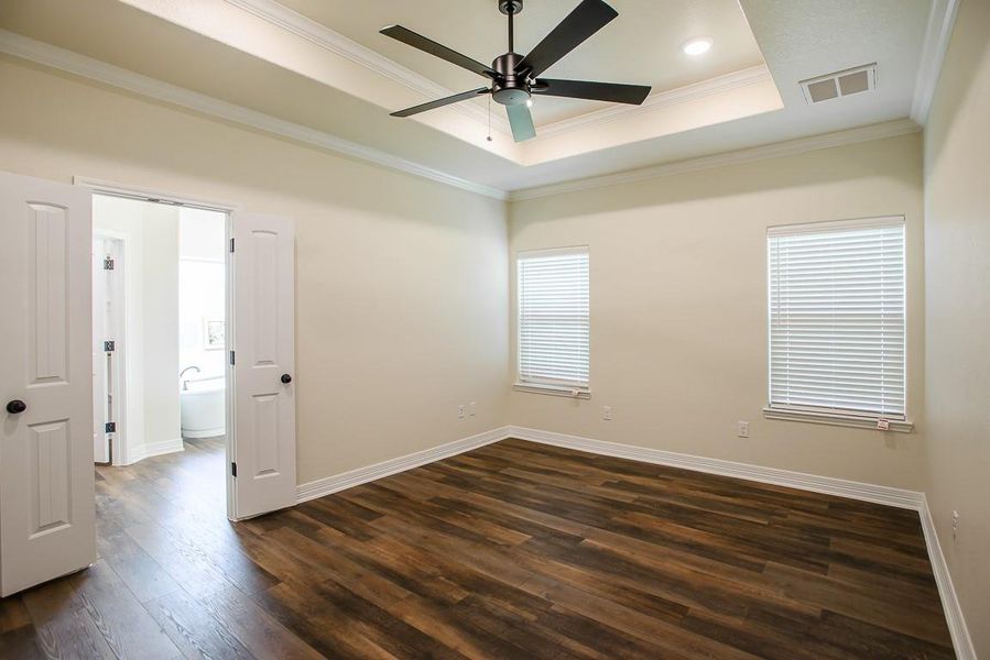 Spare room featuring crown molding, a tray ceiling, dark wood-type flooring, ceiling fan, and recessed lighting Spare room featuring crown molding, a tray ceiling, dark wood-type flooring, ceiling fan, and recessed lighting