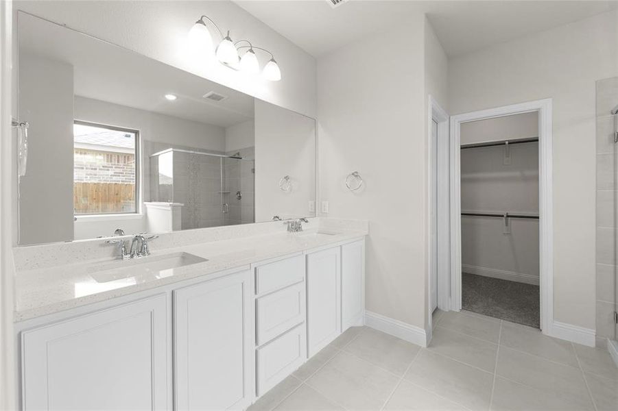 Bathroom featuring a tile shower, tile flooring, and double vanity