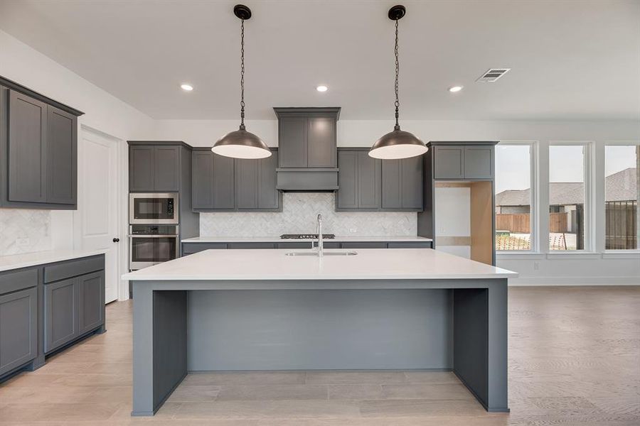 Kitchen with gray cabinets, a breakfast bar, stainless steel appliances, light stone countertops, and decorative backsplash Kitchen with gray cabinets, a breakfast bar, stainless steel appliances, light stone countertops, and decorative backsplash