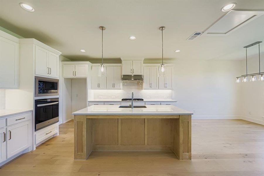 Kitchen with decorative light fixtures, white cabinets, recessed lighting, and stainless steel appliances