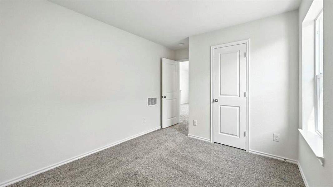 Neutral-toned interior room featuring light gray carpeting and white trim