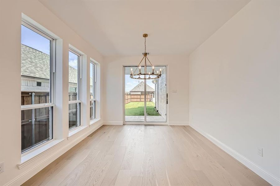 Unfurnished dining area featuring light hardwood / wood-style flooring and an inviting chandelier