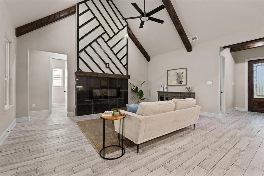 Living area featuring high vaulted ceiling, beamed ceiling, a ceiling fan, and light wood-style flooring