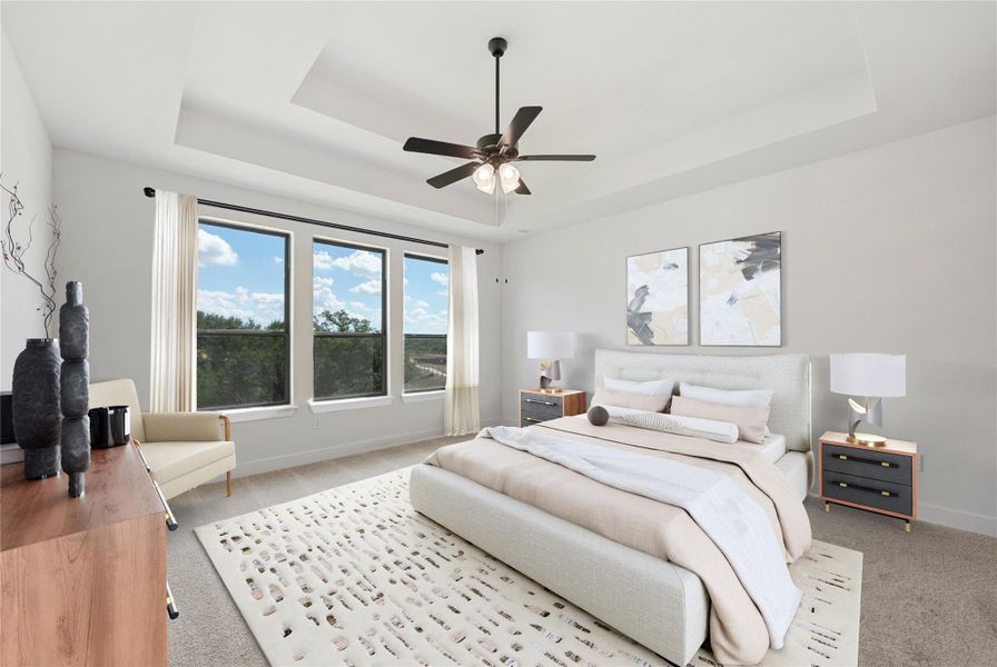 Carpeted bedroom featuring a raised ceiling and a ceiling fan