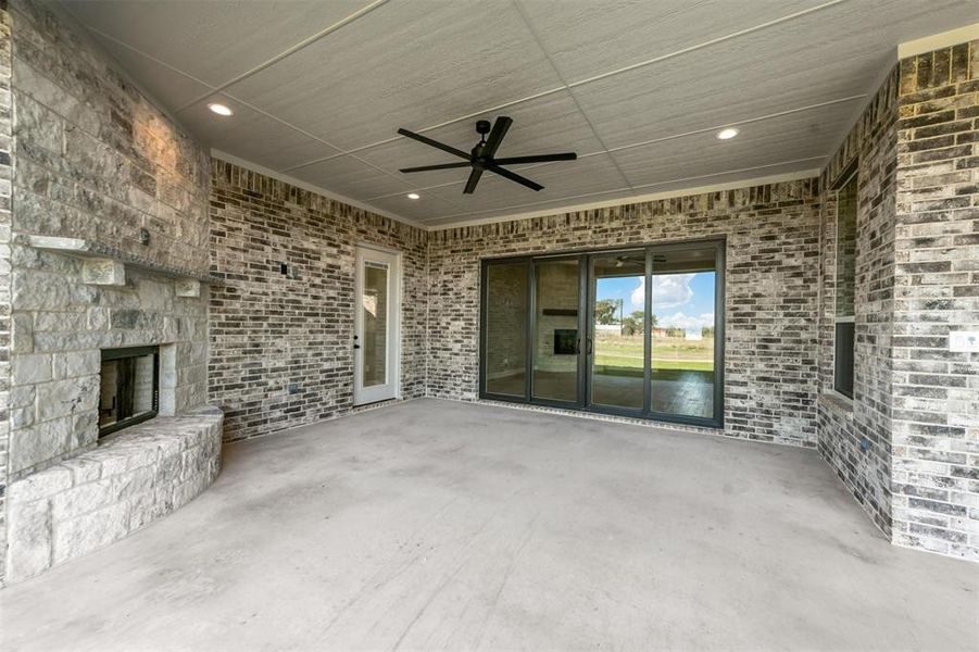 View of patio / terrace with an outdoor stone fireplace and ceiling fan