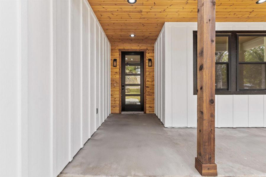 Entrance to property featuring exterior lighting and wood trim