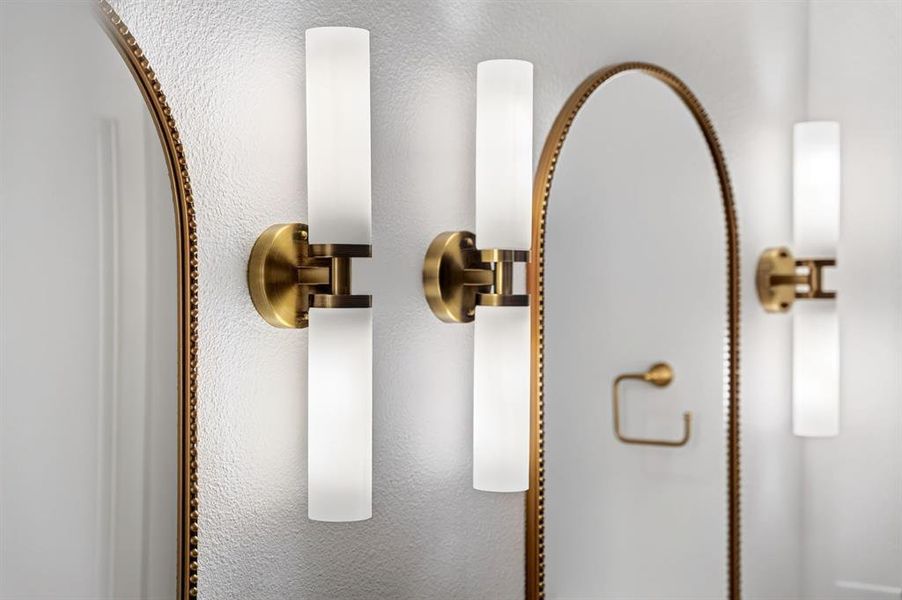 Modern bathroom lighting featuring vertical frosted glass sconces with brass hardware
