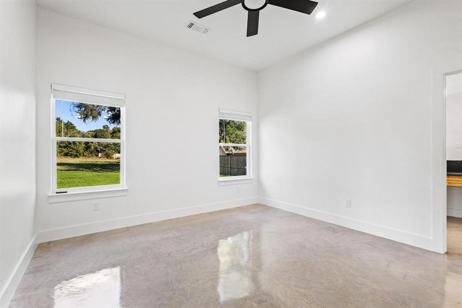 Primary bedroom with concrete floors and recessed lighting, ensuite bathroom