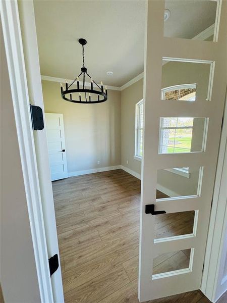 Foyer with crown molding, light wood-type flooring, and a chandelier Foyer with crown molding, light wood-type flooring, and a chandelier