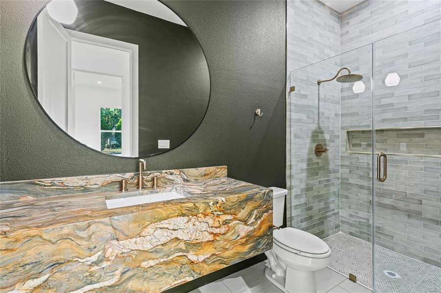 Bathroom with a textured wall, tile patterned floors, a shower stall, and vanity