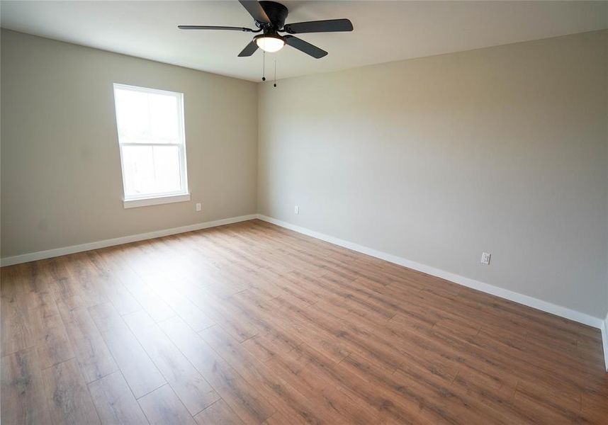Empty room with wood finished floors and a ceiling fan