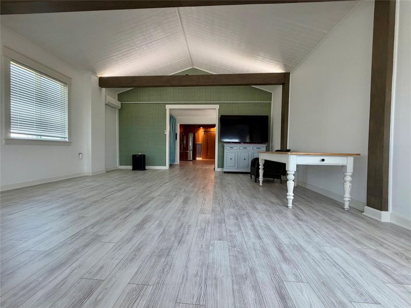 A spacious common area features high vaulted ceilings and light wood flooring, offering a versatile layout.
