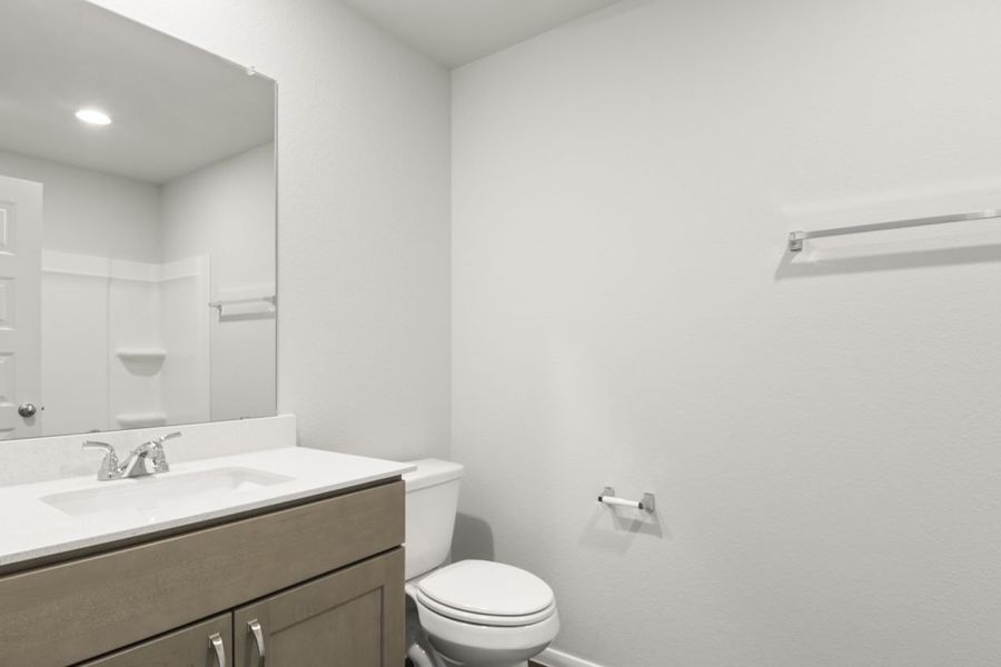 Image of a bathroom with light grey walls and a white vanity with a large mirror