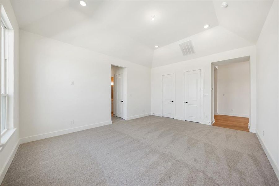 Unfurnished bedroom with light carpet, recessed lighting, and vaulted ceiling