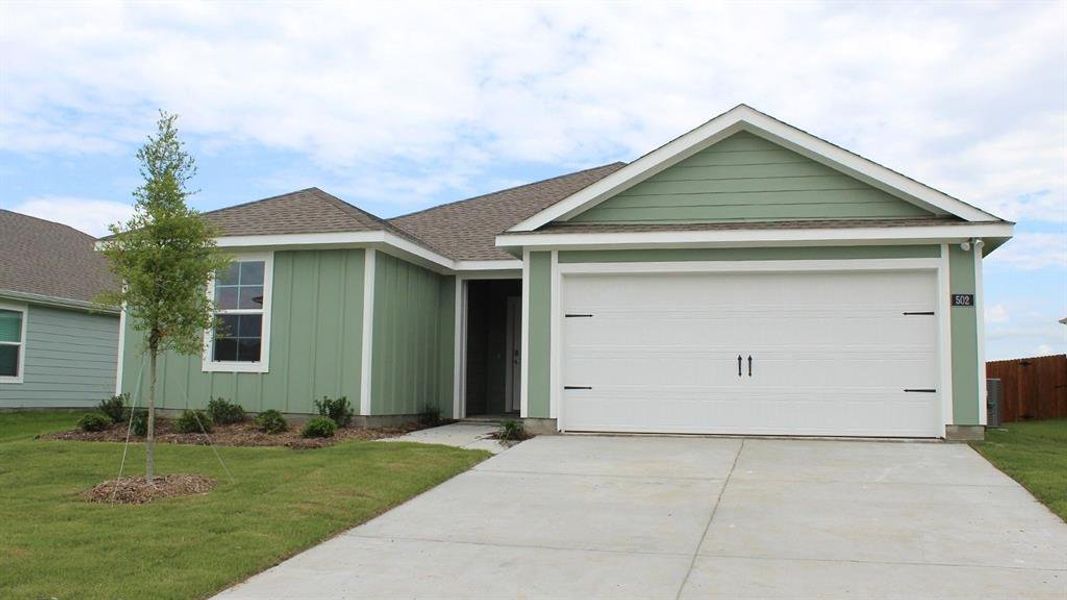 Single-story home featuring a two-car garage with decorative hardware, a light green siding exterior, and a brown shingle roof Single-story home featuring a two-car garage with decorative hardware, a light green siding exterior, and a brown shingle roof