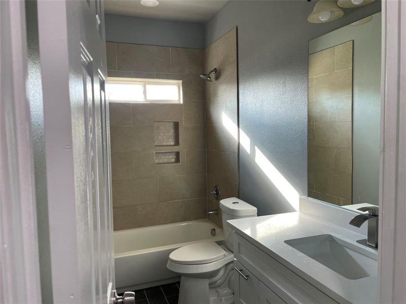 Full bathroom with vanity, toilet, tiled shower / bath combo, and tile patterned floors