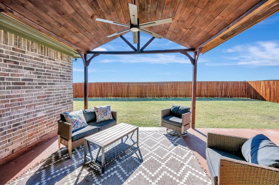 Fenced backyard featuring a patio, an outdoor hangout area, and ceiling fan