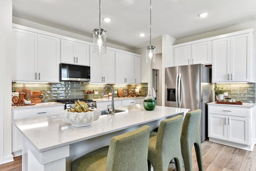 White cabinetry and quartz countertops pair with a central island and recessed lighting. White cabinetry and quartz countertops pair with a central island and recessed lighting.
