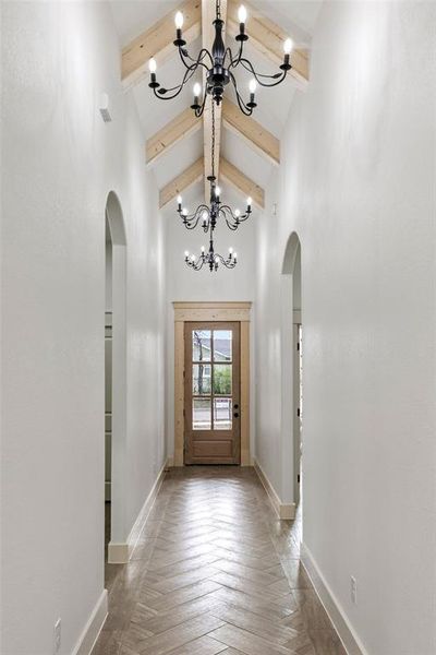 Entryway with hanging lights, parquet floors, and arched walkways