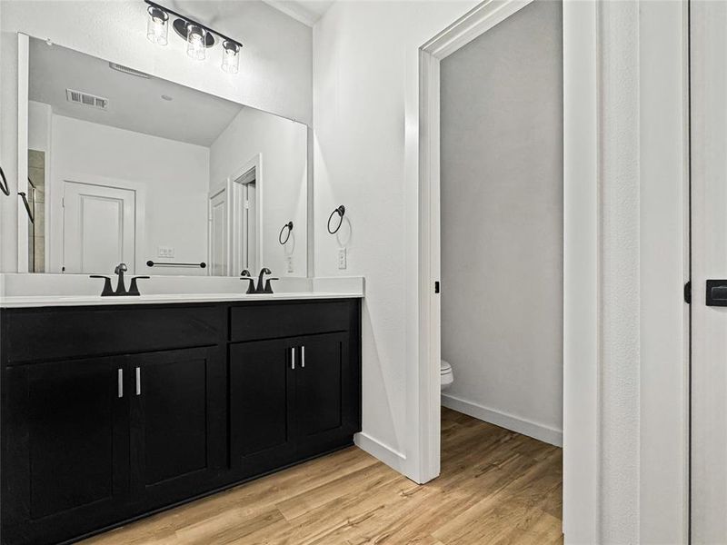 Full bath featuring double vanity, light wood-style flooring, and a shower Full bath featuring double vanity, light wood-style flooring, and a shower