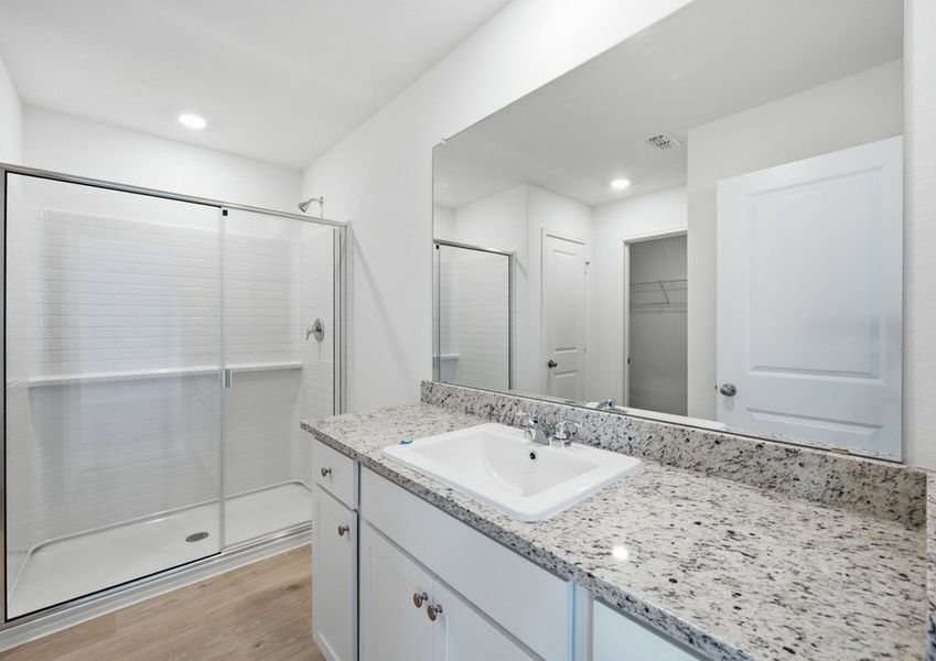 Primary bathroom featuring a vanity with granite countertop and a glass-enclosed walk-in shower. Primary bathroom featuring a vanity with granite countertop and a glass-enclosed walk-in shower.