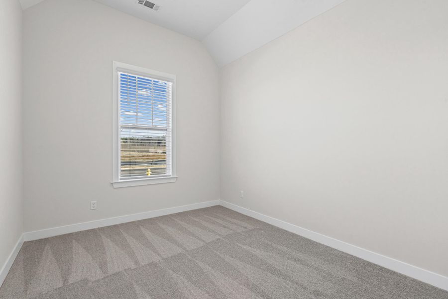 Unfurnished room with vaulted ceiling and carpet floors Unfurnished room with vaulted ceiling and carpet floors