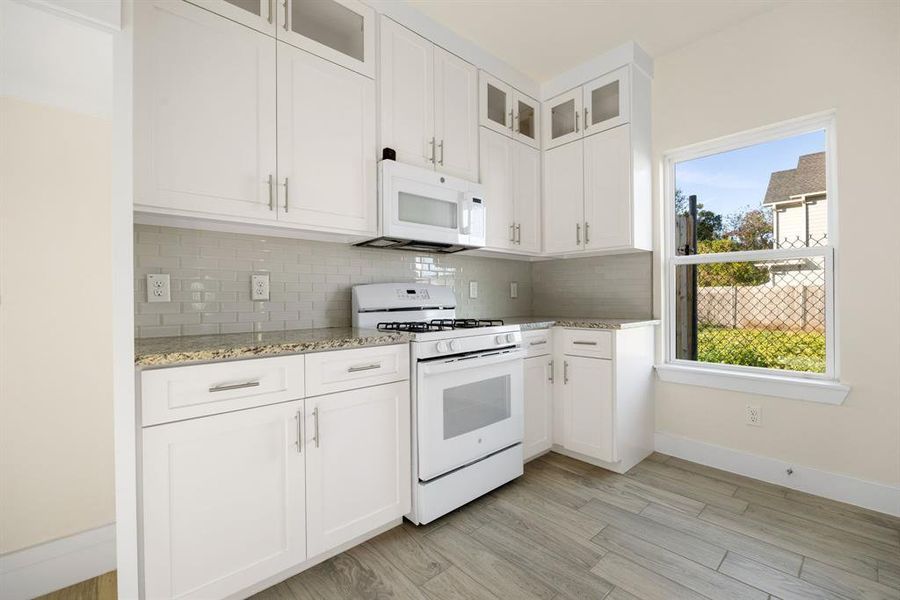 This stunning kitchen displays such a beautiful white cabinets, custom neutral paint, granite countertops, light modern backsplash, and new appliances, breakfast bar, recessed lighting, high ceilings and walk in pantry.