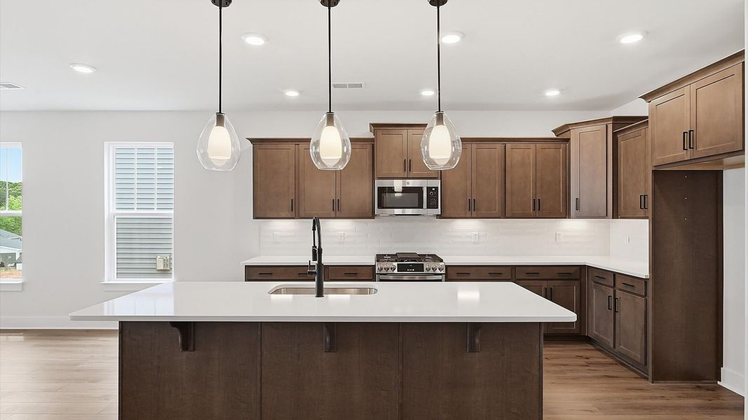 Tasteful kitchen with oversized island and stylish pendant lighting—crafted to high standards located at Iris Meadows