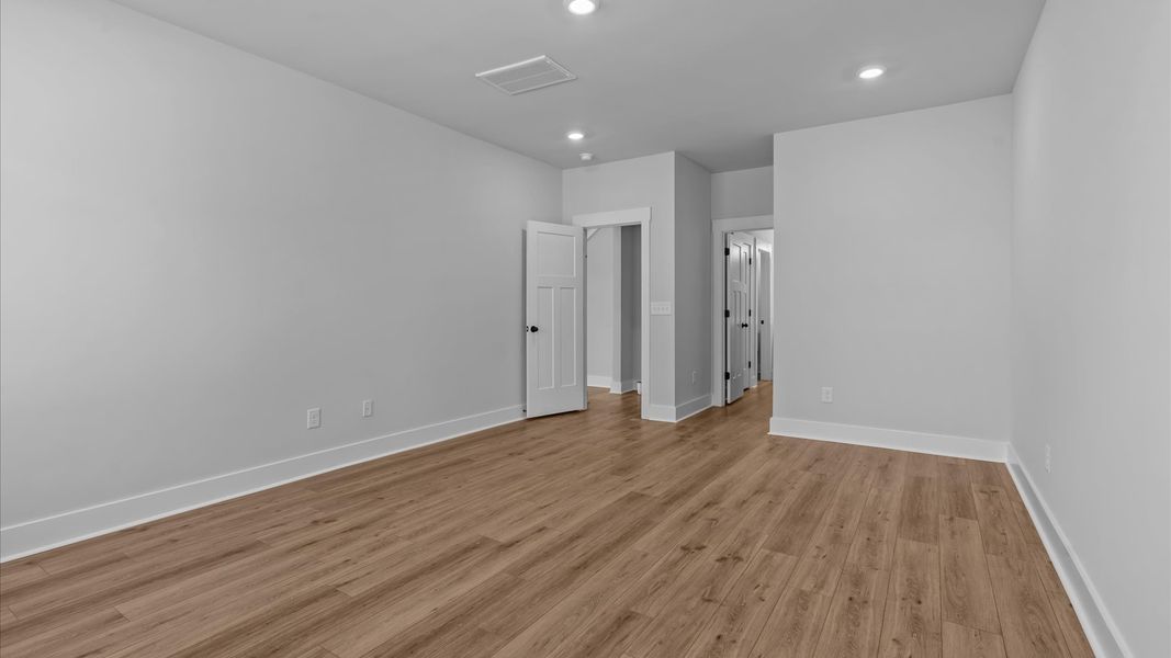 Superior design meets vibrant comfort in this primary suite with hardwood floors and walk-in closet