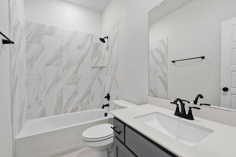 A crisp, contemporary bathroom showcases a sleek vanity and tiled shower-tub combination.