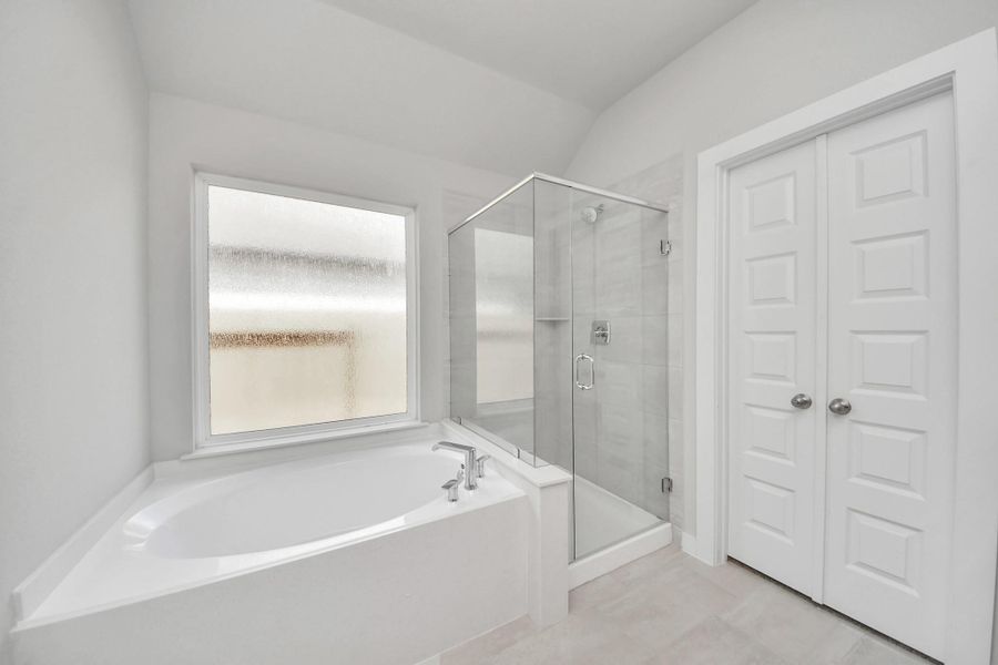 This additional view of the primary bath features a walk-in shower with the tile surround and separate garden tub perfect for soaking after a long day. Sample photo of completed home with similar floor plan. Actual colors and selections may vary.