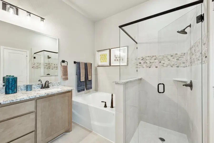 Bathroom with granite vanity, soaking tub, and glass-enclosed walk-in shower with tile accent strip Bathroom with granite vanity, soaking tub, and glass-enclosed walk-in shower with tile accent strip