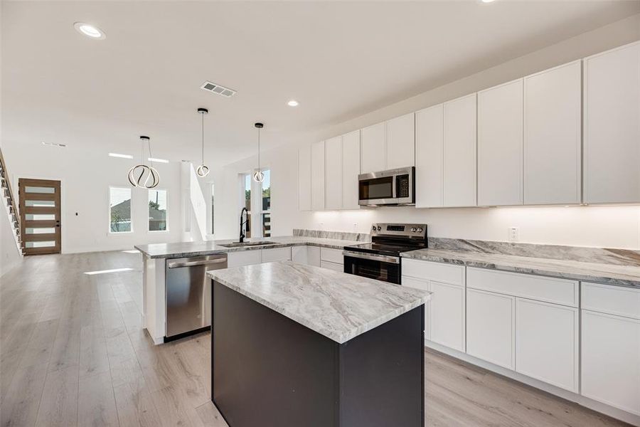 Kitchen featuring a center island, white cabinets, stainless steel appliances, a peninsula, and recessed lighting Kitchen featuring a center island, white cabinets, stainless steel appliances, a peninsula, and recessed lighting