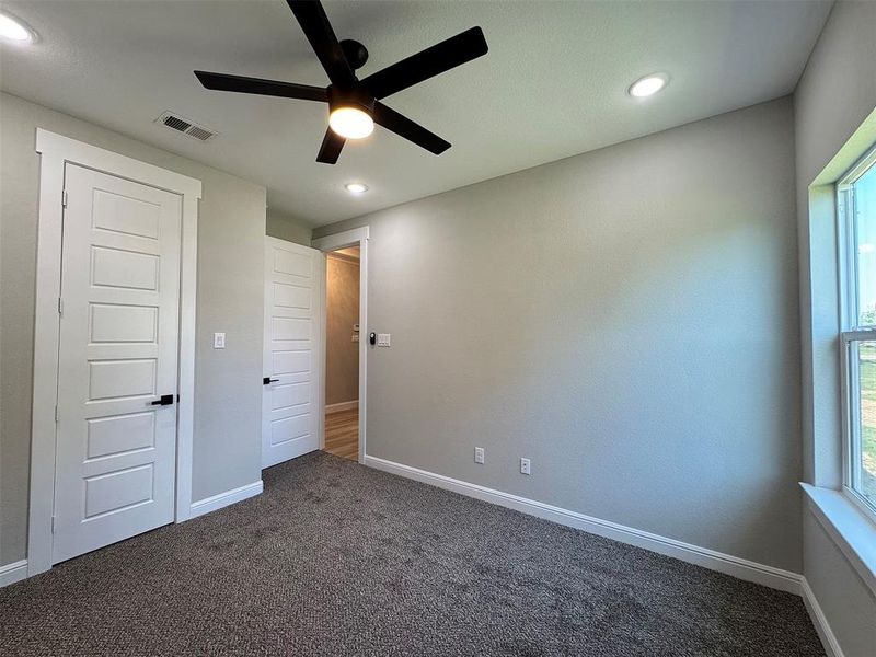 Carpeted room featuring a ceiling fan with integrated lighting, recessed lighting, white trim, and panel doors with matte black hardware
