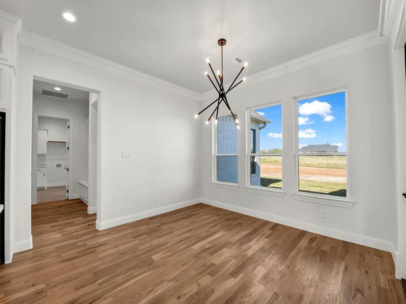 Unfurnished dining area with hardwood / wood-style floors, an inviting chandelier, and ornamental molding