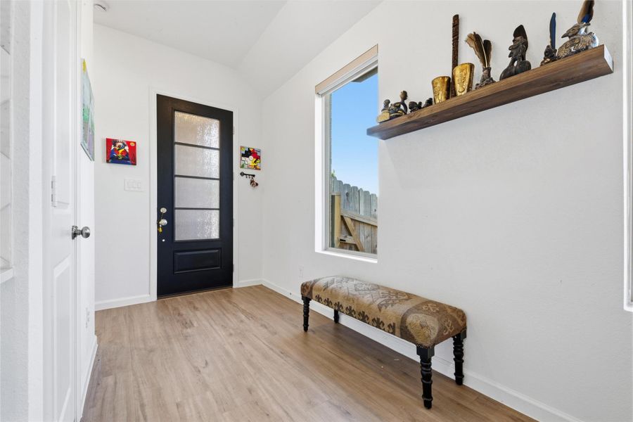 The foyer area has light wood flooring, and the window offers natural light.