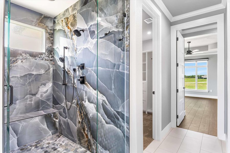 Full bathroom featuring crown molding, a marble finish shower, a ceiling fan, baseboards, and tile patterned flooring Full bathroom featuring crown molding, a marble finish shower, a ceiling fan, baseboards, and tile patterned flooring