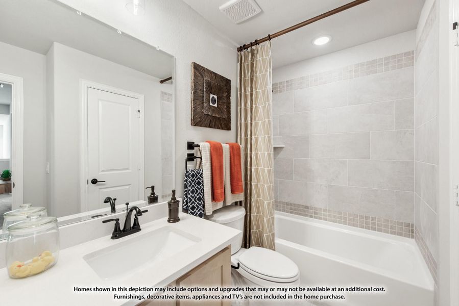 Bathroom with white vanity, dark fixtures, and tiled shower-tub combo with curtain