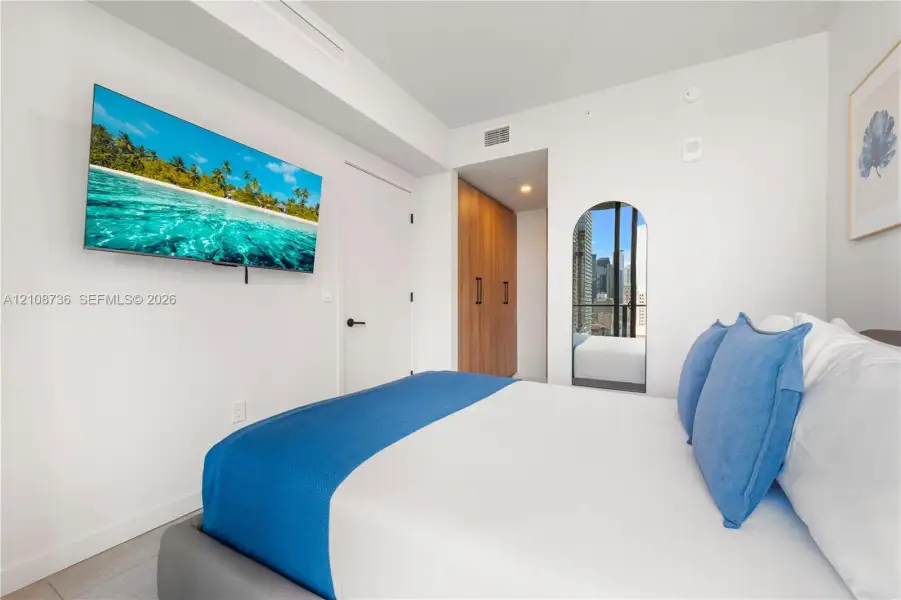 Room featuring an arched full-length mirror, wood-finish built-in cabinetry, and neutral wall-finish flooring Room featuring an arched full-length mirror, wood-finish built-in cabinetry, and neutral wall-finish flooring
