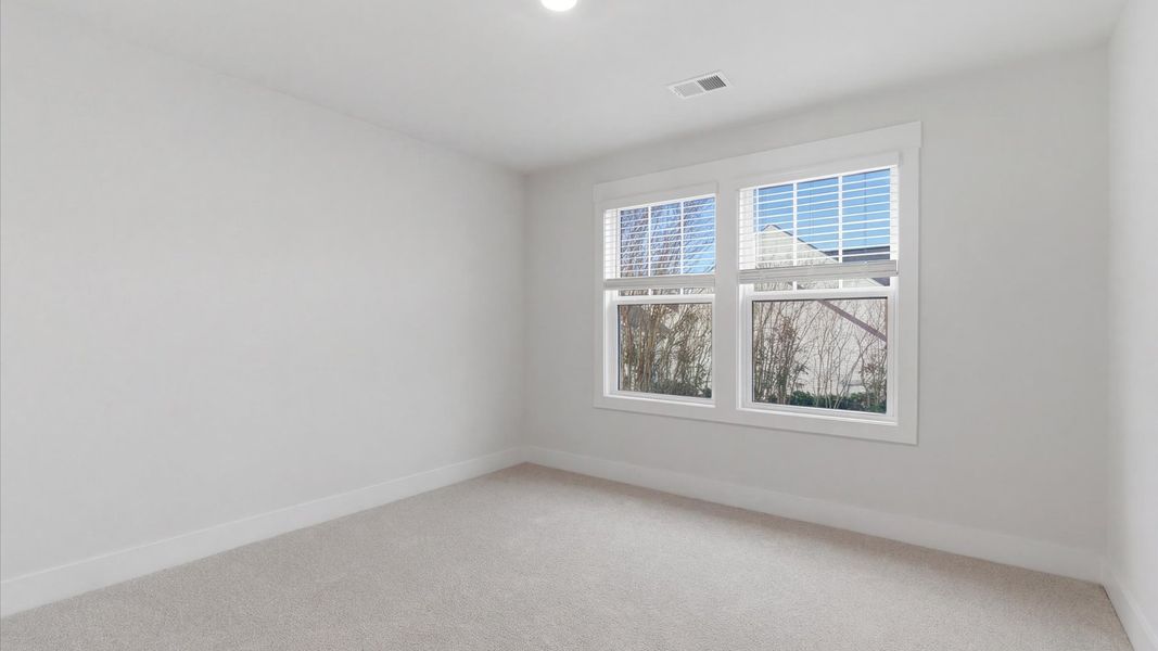 Highly functional bedroom with large windows, carpeted flooring, and tasteful finishes throughout by DRB Homes
