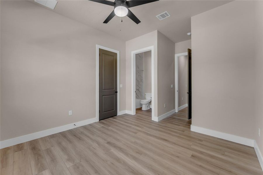 Unfurnished bedroom featuring light wood-style flooring, a ceiling fan, and ensuite bathroom