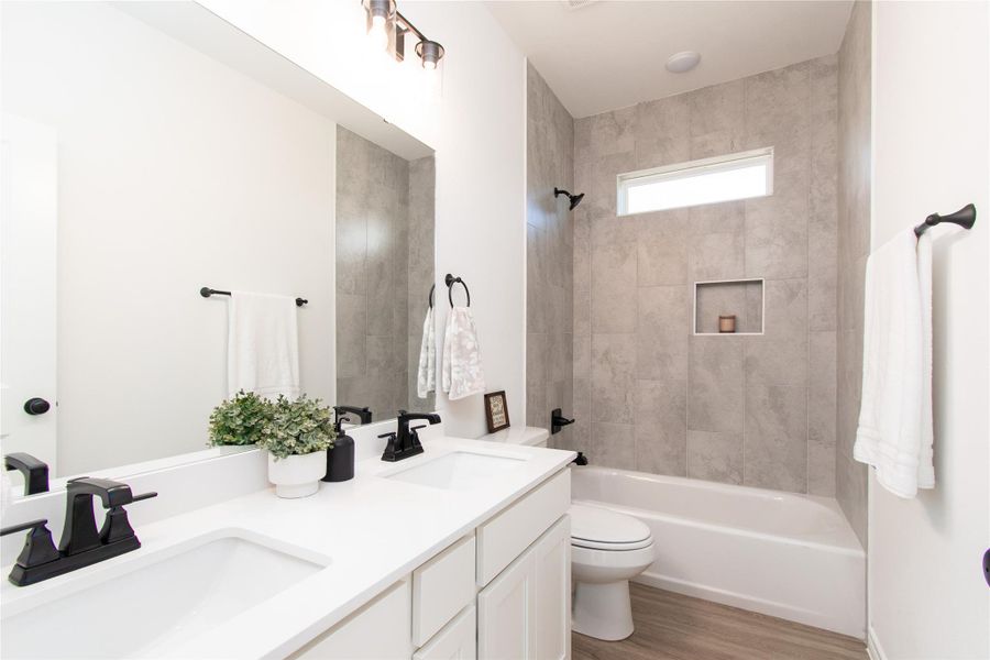 Full bath with bathtub / shower combination, double vanity, and light wood-type flooring