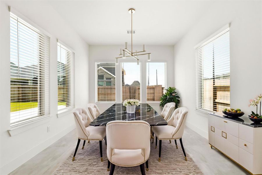 The light-filled dining area provides a serene setting for formal gatherings, illuminated by a custom designer chandelier and surrounded by views of the private backyard. Virtually staged.