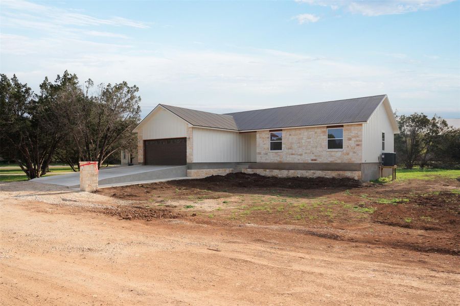View of front of house featuring a metal roof, driveway, and a garage