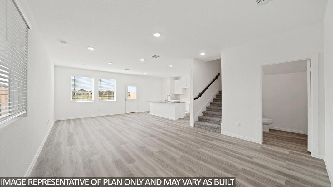 Open-concept main living area featuring wide plank wood-finish flooring, recessed lighting, and large windows