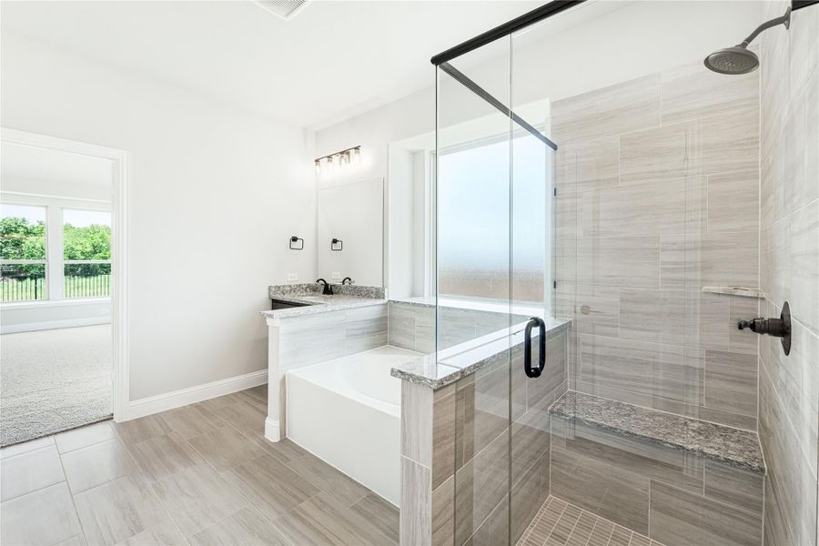 Master bathroom with glass walk-in shower, soaking tub, double vanity, and gray tile floors Master bathroom with glass walk-in shower, soaking tub, double vanity, and gray tile floors