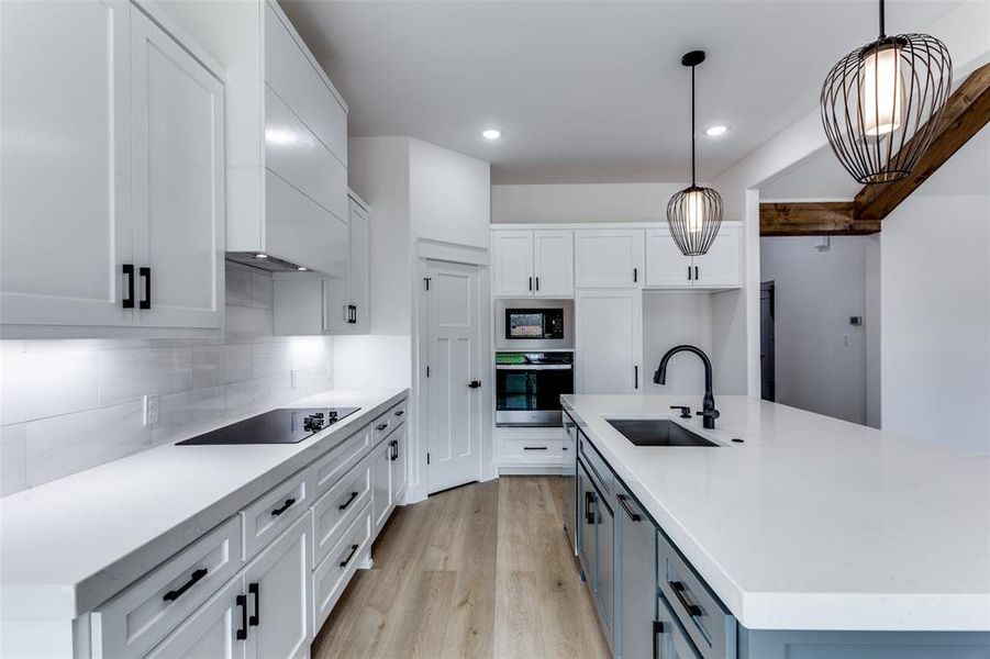 Kitchen featuring decorative backsplash, light wood-style floors, black appliances, white cabinetry, and a sink